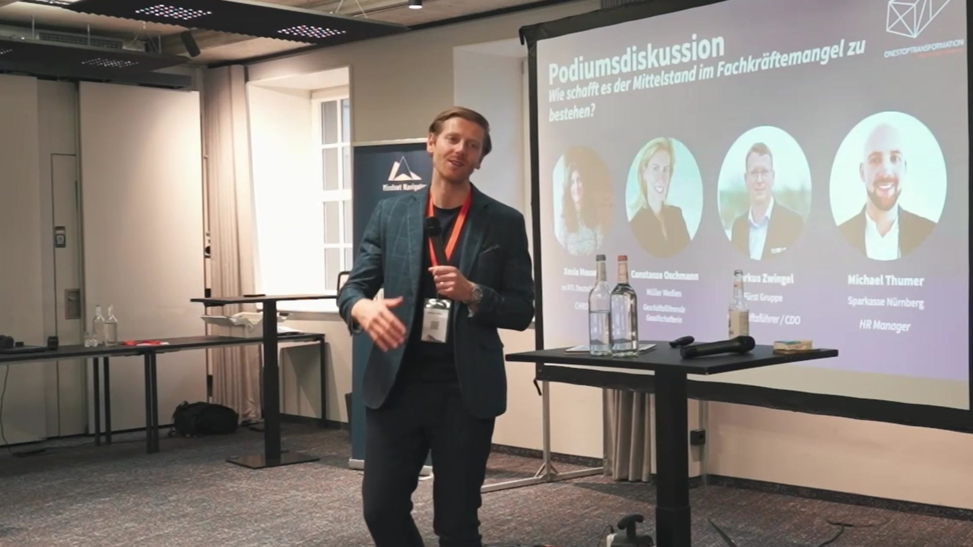 Redner auf der Bühne vor Präsentationsfolien