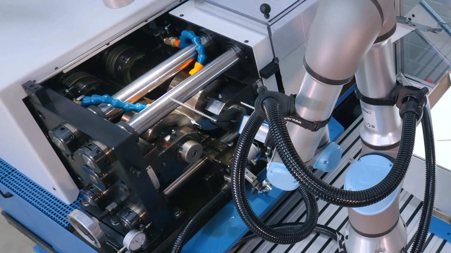 Roboterarm des RWT FRM legt ein Rohteil in den Walzkopf einer Gewindewalzmaschine ein