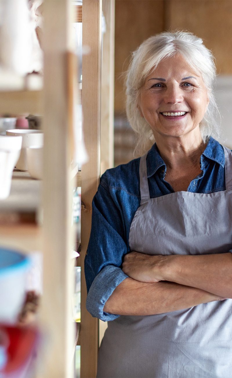 Confident mature master in overalls greeting his colleague or subordinate by handshake